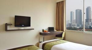 una camera d'albergo con due letti e una televisione di Grand Cemara Hotel a Giacarta