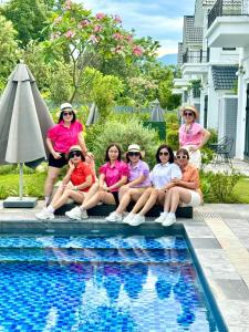 a group of women sitting next to a swimming pool at Vườn vua resort- Sunvillas in Ðồng Phú