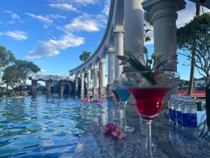 two wine glasses sitting on a table next to a swimming pool at Vườn vua resort- Sunvillas in Ðồng Phú