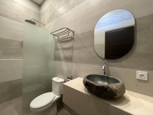 een badkamer met een stenen wastafel en een spiegel bij Saltera Kedungu in Tanah Lot