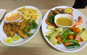 two plates of food with fish and vegetables and french fries at Carambola Resort in Negombo