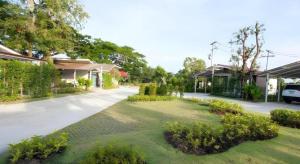 een huis met een oprit en een tuin met struiken bij Baan Kula Mahasarakam in Ban Nong Chik