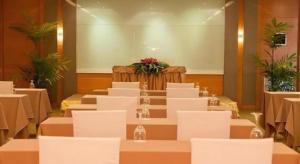 een kamer met witte tafels, witte stoelen en bloemen bij Clef Hotel Bangkok in Ban Khlong Samrong