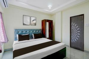 a bedroom with a large bed with a blue headboard at Hotel O Ring Road Nagpur Formerly Glory Inn in Khāpri