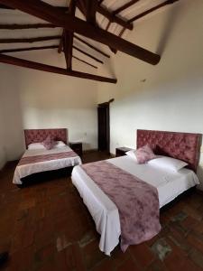 two beds in a large room with wooden ceilings at Cabaña VillaMaria in Villanueva +29 photos