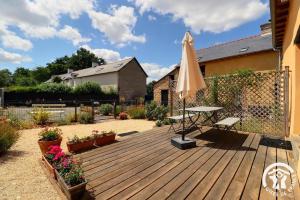 a wooden deck with a table and an umbrella at Les 3 epines in Rennes
