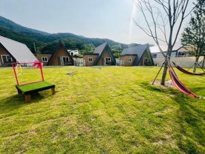 a park with a swing and a hammock in the grass at Danyang Semo House in Danyang