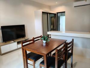 a dining room with a table and chairs and a television at Le Wadee Residence in Bang Tao Beach