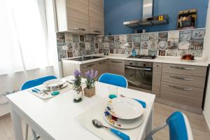 ラ・スペツィアにあるByron & Shelley Apartmentsのキッチン(白いテーブル、青い椅子付)