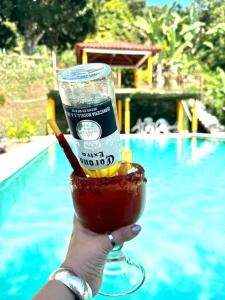 a hand holding a drink with a straw in it next to a pool at Finca San Antonio in Pluma Hidalgo