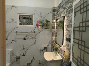 a bathroom with a marble wall with a sink and a mirror at Stay Roside Villa Hikkaduwa in Hikkaduwa +17 photos