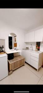 a kitchen with white cabinets and a sink and a refrigerator at Atacama container in Brasília +3 photos