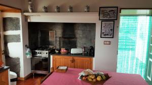 a kitchen with a stove and a table with a bowl of fruit at Casa do Paim in São Roque do Pico