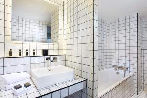 ein Badezimmer mit einem Waschbecken, einer Badewanne und einem Spiegel in der Unterkunft La Maison Champs Elysées in Paris