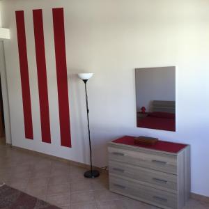 バレストラーテにあるRoby Suite Homeの赤と白の壁の客室で、ドレッサーが備わります。