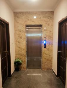una porta di un ascensore in metallo in una stanza con un muro di pietra di Ebenezer Plaza a Nedumbassery