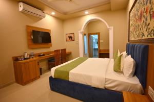 a bedroom with a bed and a desk and a television at The Van Bagh Ranthambore in Sawāi Mādhopur