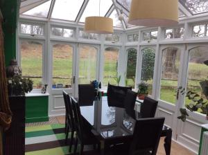 a conservatory with a table and chairs and windows at Bridge Cottage in Midhurst