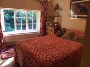 a bedroom with a bed and a large window at Bridge Cottage in Midhurst