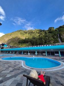 a person laying on a bench next to a swimming pool at Suite Matrimonial 3plz con cocina y garage in Baños