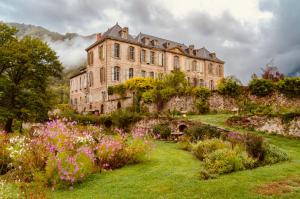 a large building on top of a hill with flowers at Chateau de Gudanes in Château-Verdun