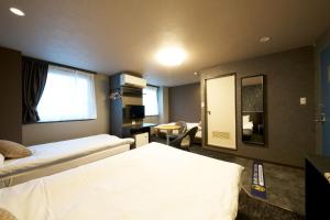 a hotel room with two beds and a desk at Hotel Areaone Naruto in Naruto