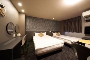 a hotel room with two beds and a desk at Hotel Areaone Naruto in Naruto