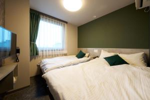 a bedroom with two beds and a large window at Hotel Areaone Naruto in Naruto +5 photos