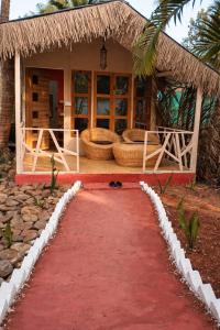 a red path leading to a house with a straw roof at Sea Shades Palolem Resort in Palolem