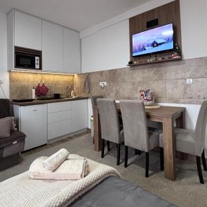 a kitchen and dining room with a table and a tv on the wall at Monte LUX 10 in Kopaonik