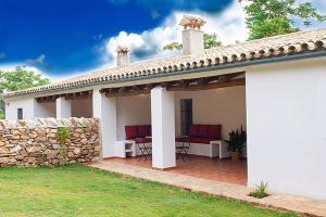 a white house with a stone wall and a patio at Casas Rurales La Lapa in El Cerro del Hierro
