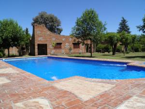 a swimming pool in front of a brick house at Cabañas La Rosada in Santa Rosa de Calamuchita