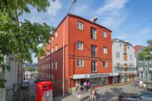 a red building on a street with people walking around it at Trondheim Fjord Suites Self Checkin And Out in Trondheim
