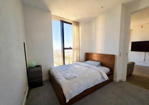 a bedroom with a bed and a large window at Sunset Sky Nest CBD 65F in Melbourne
