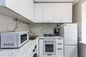 a white kitchen with white cabinets and a microwave at Гоголя 117 in Almaty