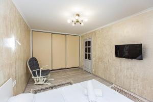 a living room with a tv and a chair at Гоголя 117 in Almaty
