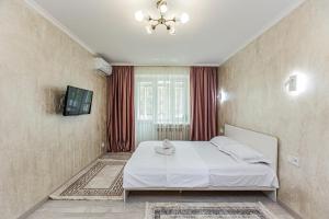 a bedroom with a white bed and a television at Гоголя 117 in Almaty