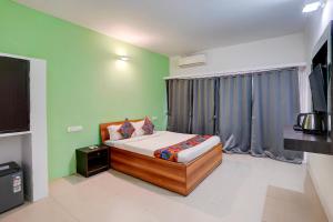 een slaapkamer met een bed in een kamer met groene muren bij FabHotel Bay Breeze in Morjim