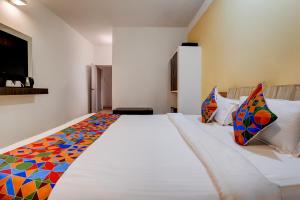 een slaapkamer met een groot wit bed met kleurrijke kussens bij FabHotel Bay Breeze in Morjim