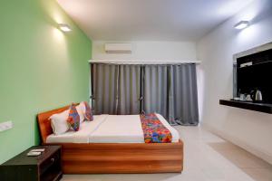 een slaapkamer met een bed en een groot raam bij FabHotel Bay Breeze in Morjim