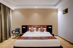 een slaapkamer met een groot bed en een stoel bij FabHotel Bay Breeze in Morjim