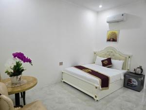 a white bedroom with a bed and a table and a table sidx sidx at Ruby Hotel Front Of Beach 2 in Bình Sum