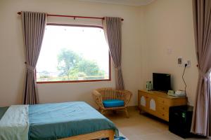 a bedroom with a bed and a window and a chair at The Sky Homestay in Ấp Khánh Phước (1)