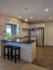 eine große Küche mit einer großen Theke und Stühlen in der Unterkunft Villa 46 in Pauanui