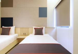 zwei Betten in einem kleinen Zimmer mit Fenster in der Unterkunft IXO Hotel Semarang in Stasiun Tawang + 3 Fotos