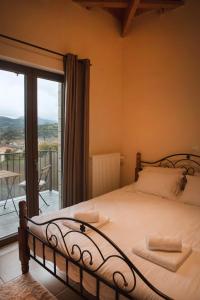 a bedroom with a bed with a view of a balcony at Τα πέτρινα στο Σκεπαστό in Kalavrita