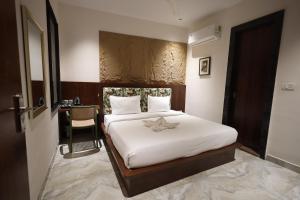 a bedroom with a bed with white sheets and a table at Hotel Destin in Gwalior