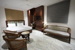een slaapkamer met een bed, een bureau en een stoel bij Hotel Destin in Gwalior