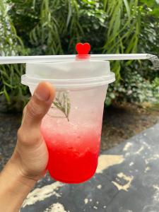 a hand holding a drink in a plastic cup at ใจกลม โฮมคาเฟ่ in Ban Hua Phrong