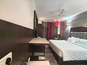 une chambre d'hôtel avec un lit et un bureau dans l'établissement POP 84200K M K Elegance Inn, à Coimbatore (Peelamedu)